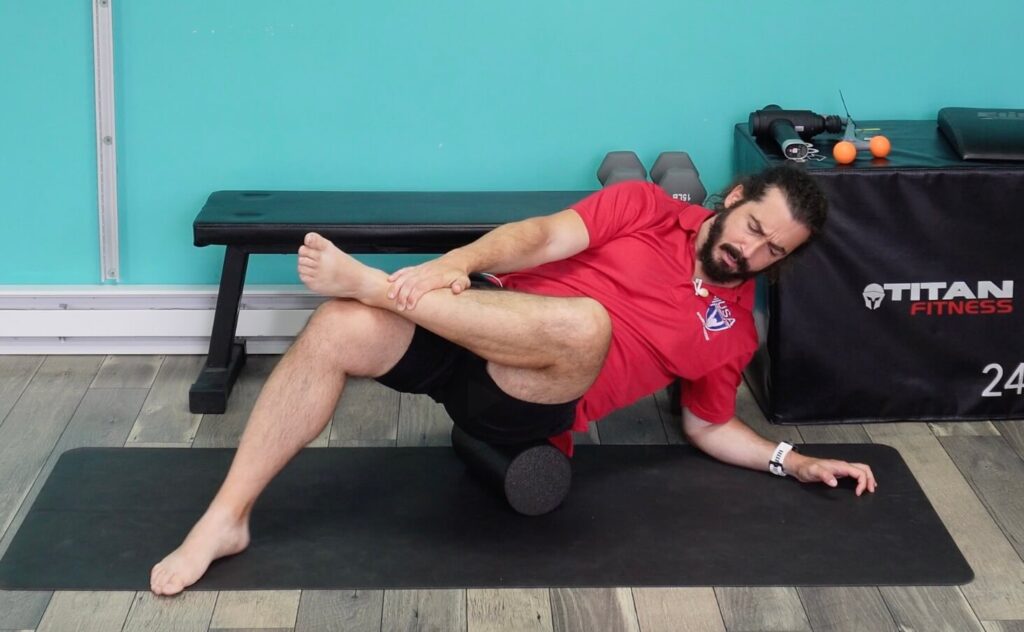 dr. john with the foam roller under his left glute to release knots and adhesions in the fascia